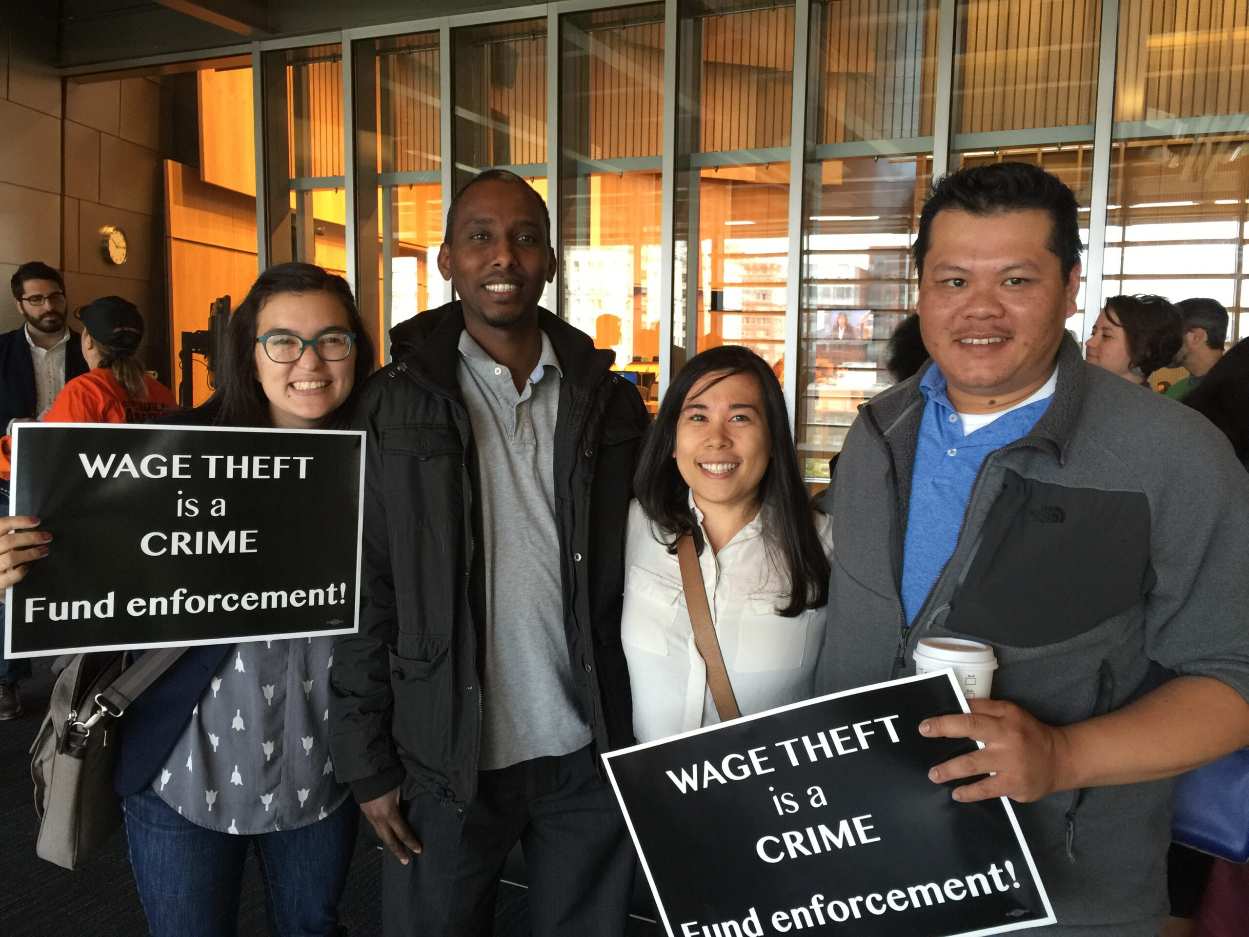 People holding signs that say, "Wage theft is a crime."